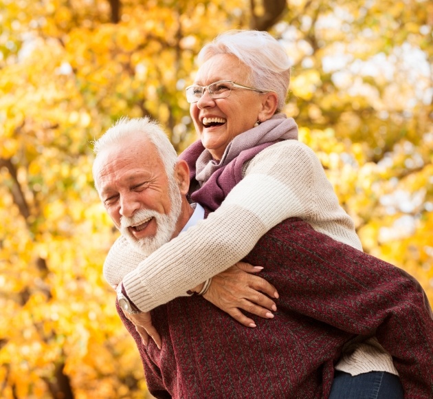 Older couple with dentures smiling outdoors