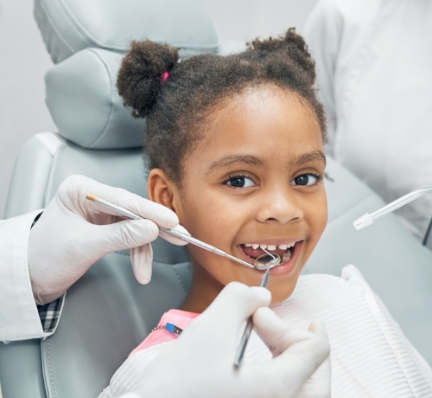Dentist examining child's smile after dental sealant treatment