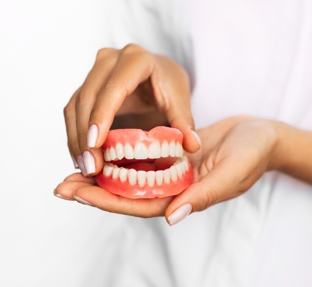 Hand holding full set of dentures