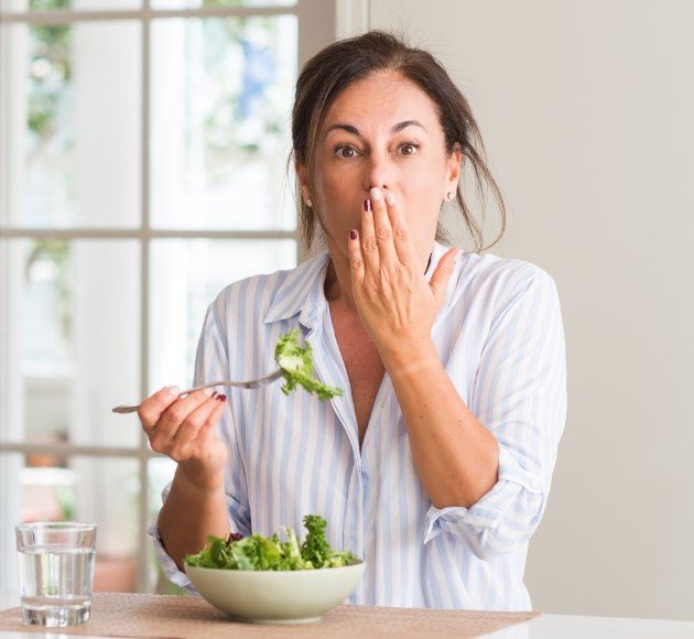 Woman in need of emergency dentistry covering her mouth