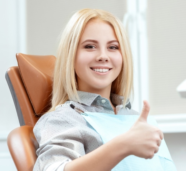 Woman smiling and giving thumbs up after dental checkup and teeth cleaning visit