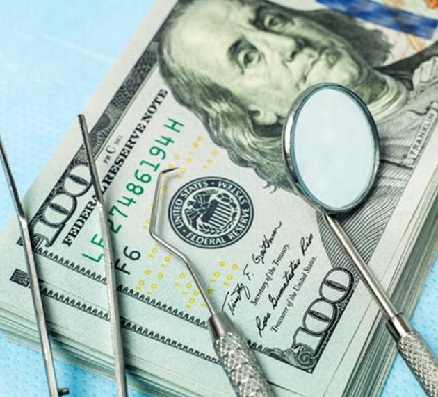 stack of money with dental tools
