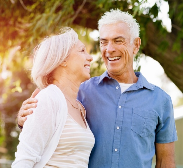 Man and woman with dental implant retained dentures smiling