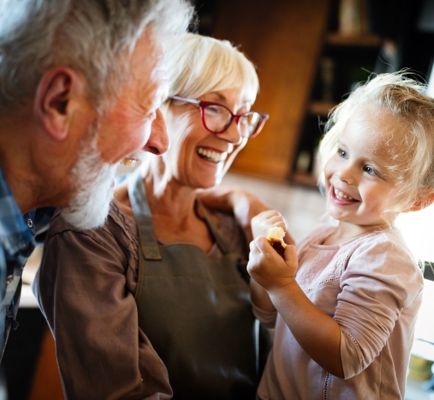 Grandparents smiling and grand child after dental implant tooth replacement