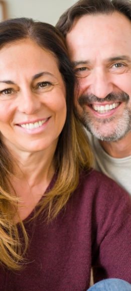 Man and woman smiling after tooth replacement with dental implants