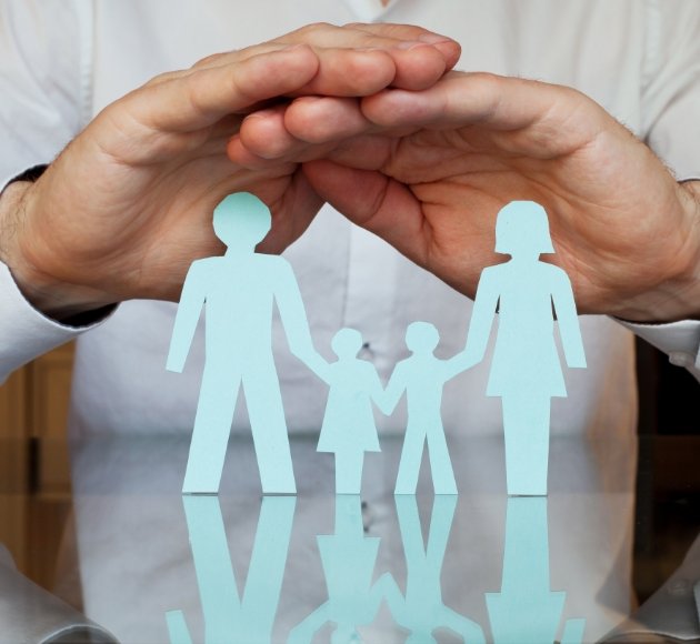 Hands covering paper cut out family