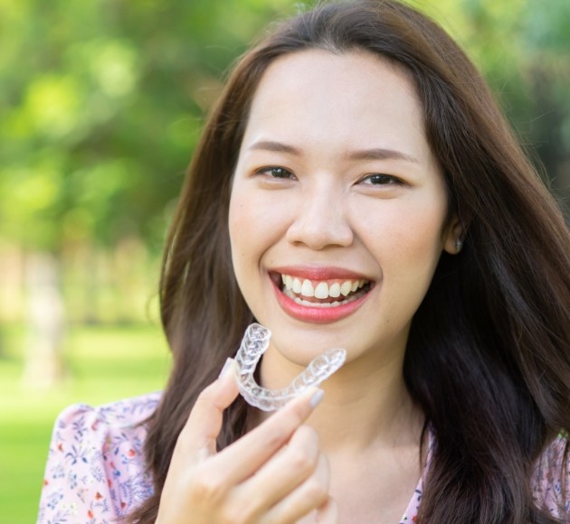 Smiling woman holding an Invisalign tray