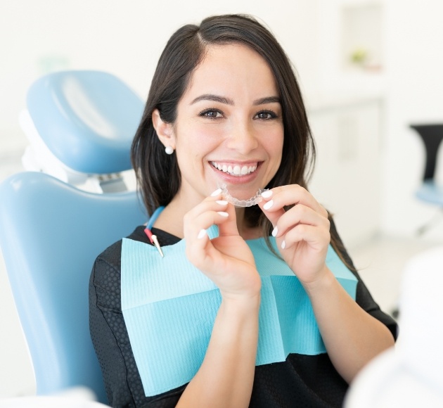 Woman in dental chair playing her Invisalign tray