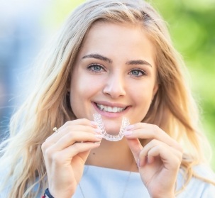 Smiling woman placing an Invisalign tray