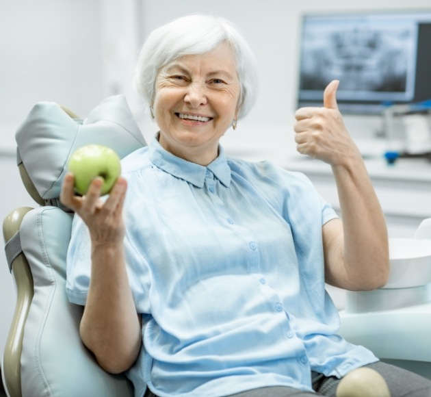 Woman with dentures smiling and giving thumbs up