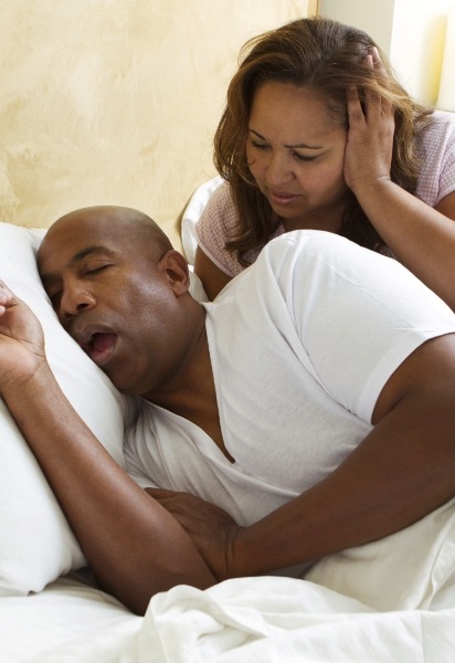 Woman frustrated with snoring man in need of sleep apnea therapy