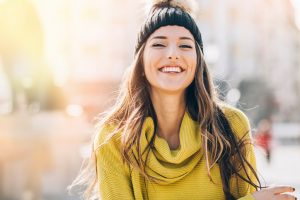Young woman smiling after seeing her cosmetic dentist in Natick