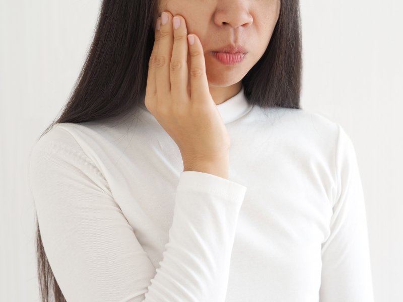 Close-up of woman in white shirt rubbing her jaw