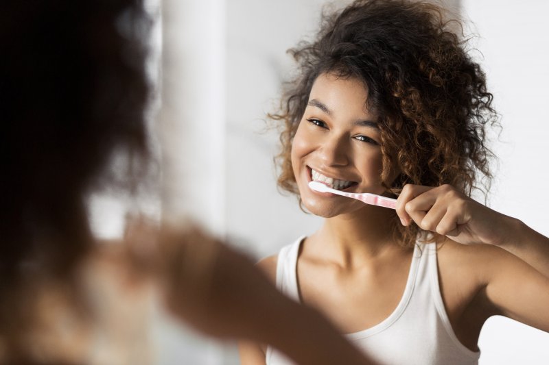 A woman celebrating oral hygiene month by brushing her teeth