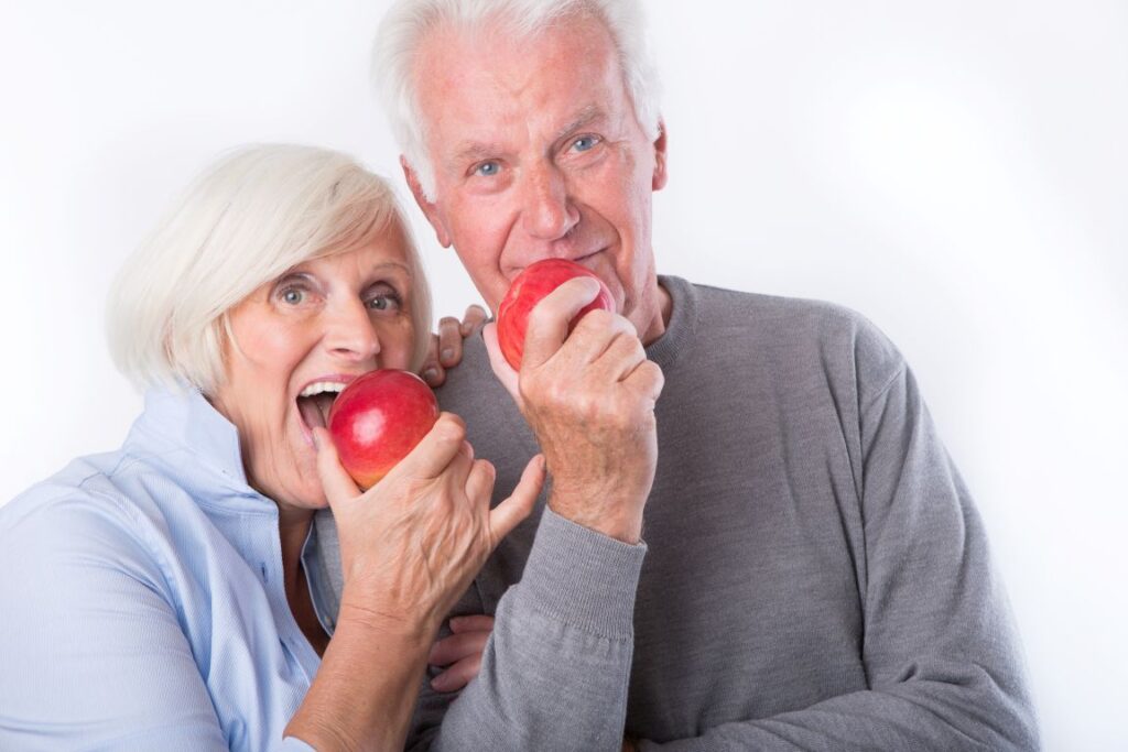 A man and woman with dentures eating apples